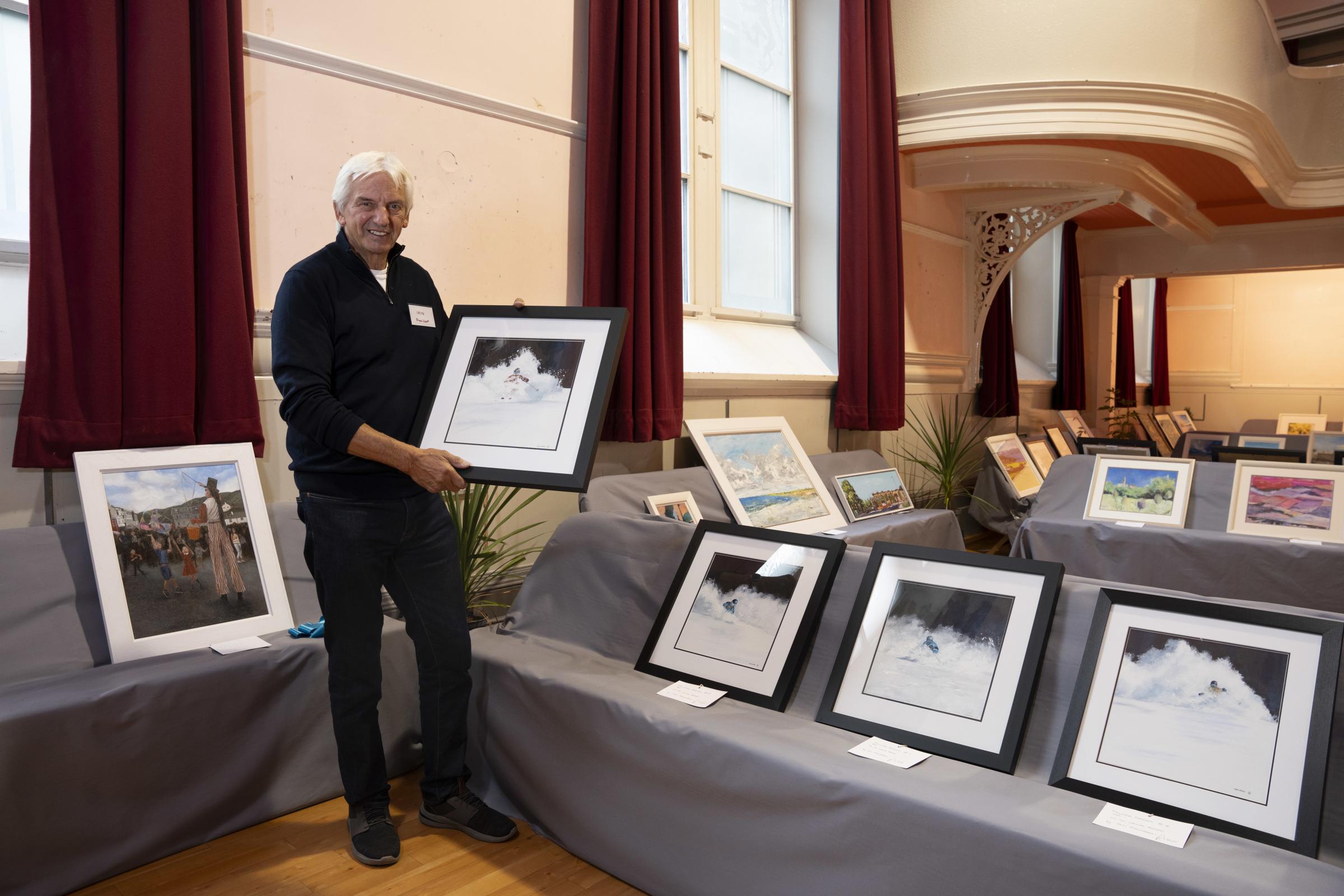 Iain Macleod with his paintings of skiiers