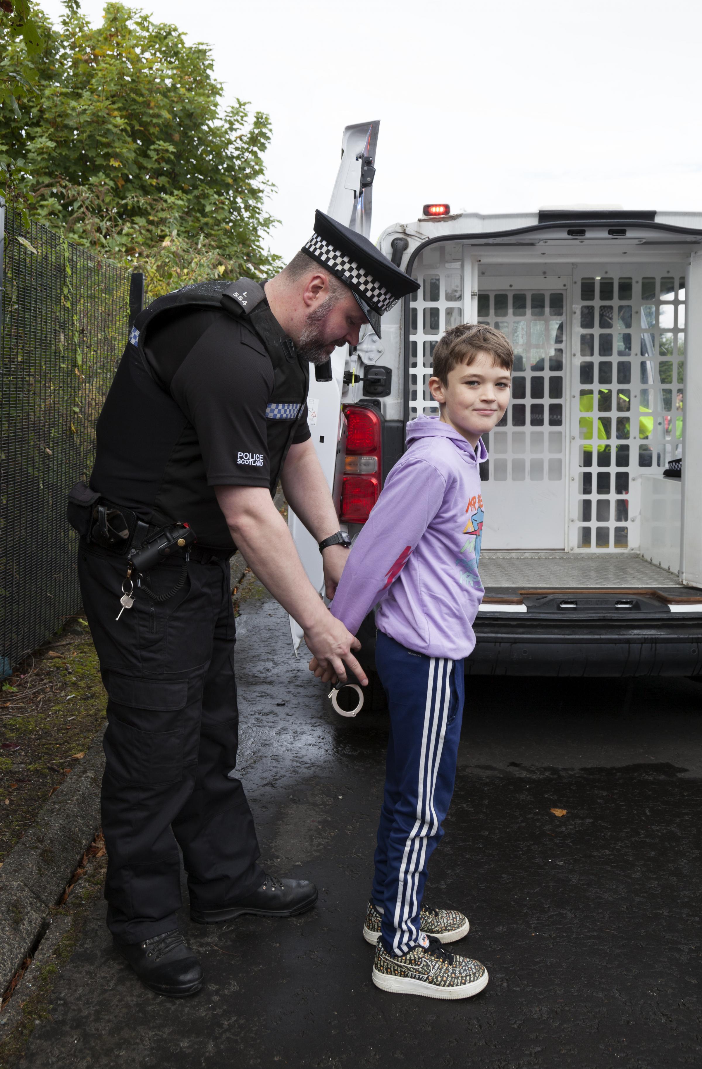 Kia Campbell being shown how handcuffs are fitted by Police officer.