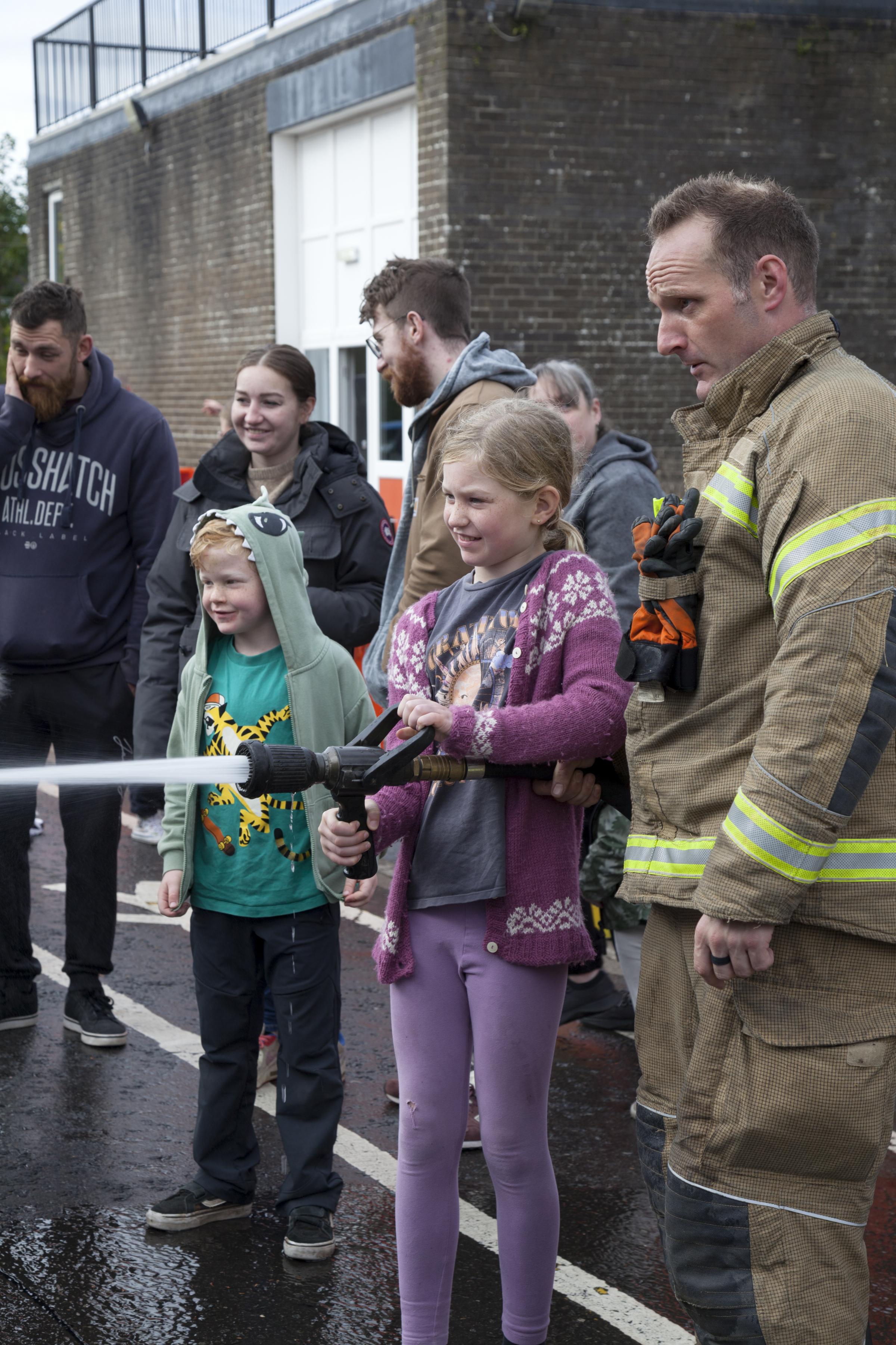 Girl learning how to use a fire hose.