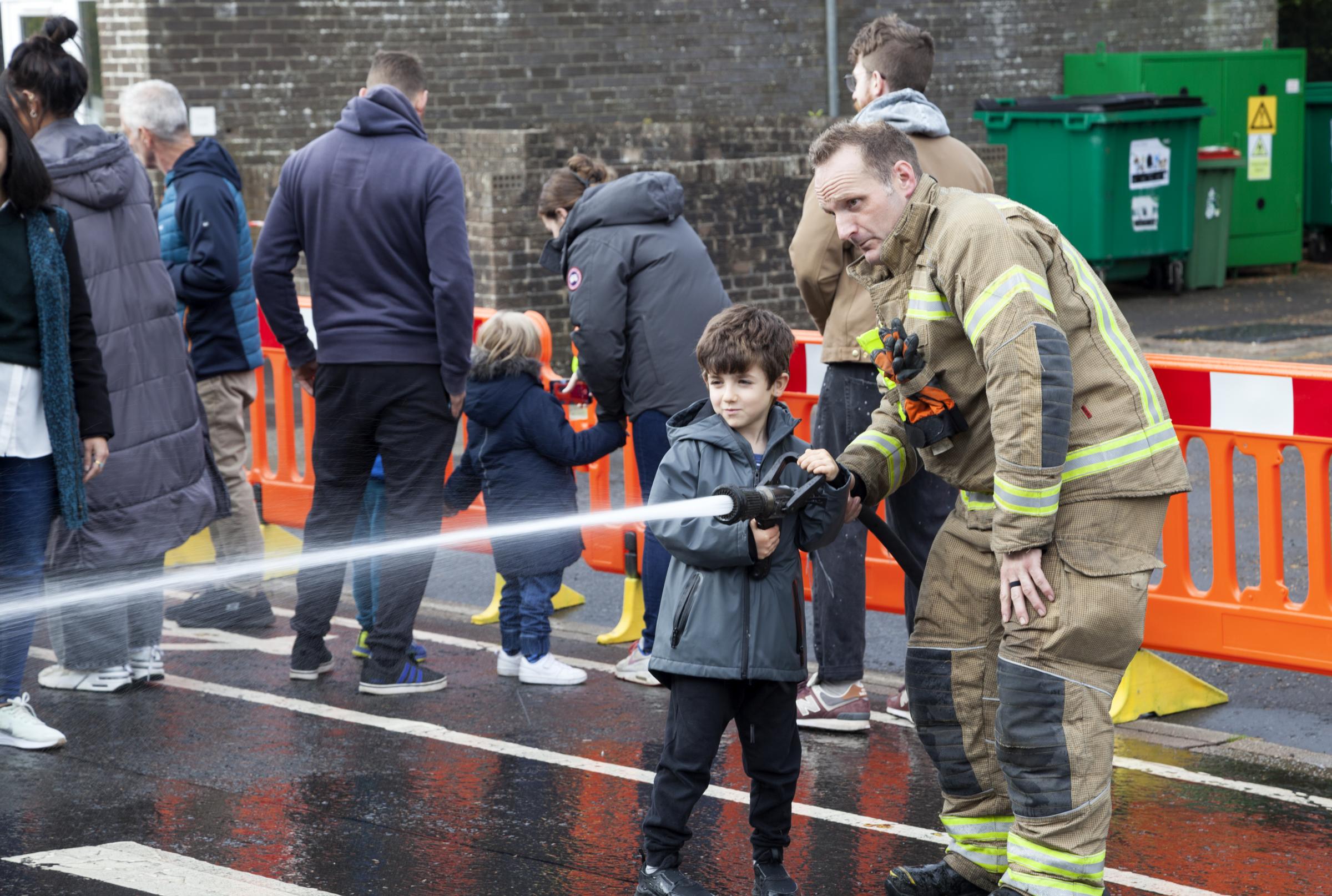 Boy learning how to use a fire hose.